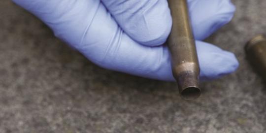 image of gloved hand holding a bullet casing