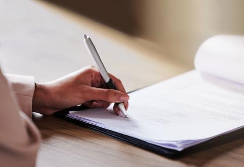 Person writing on paper with pen